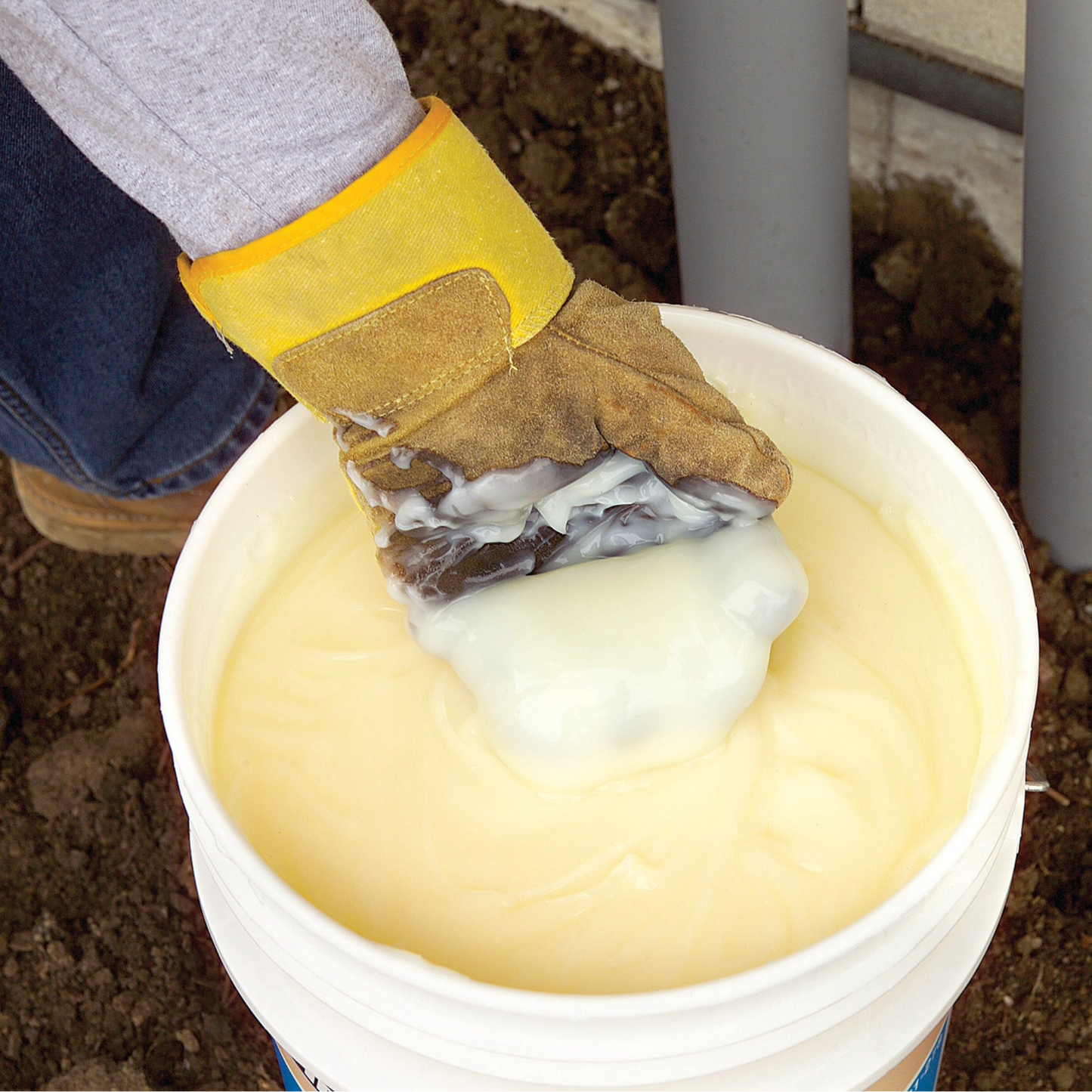 An open bucket of Ideal Yellow 77 cable lubricant with a gloved hand holding some of the lubricant