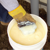 An open bucket of Ideal Yellow 77 cable lubricant with a gloved hand holding some of the lubricant